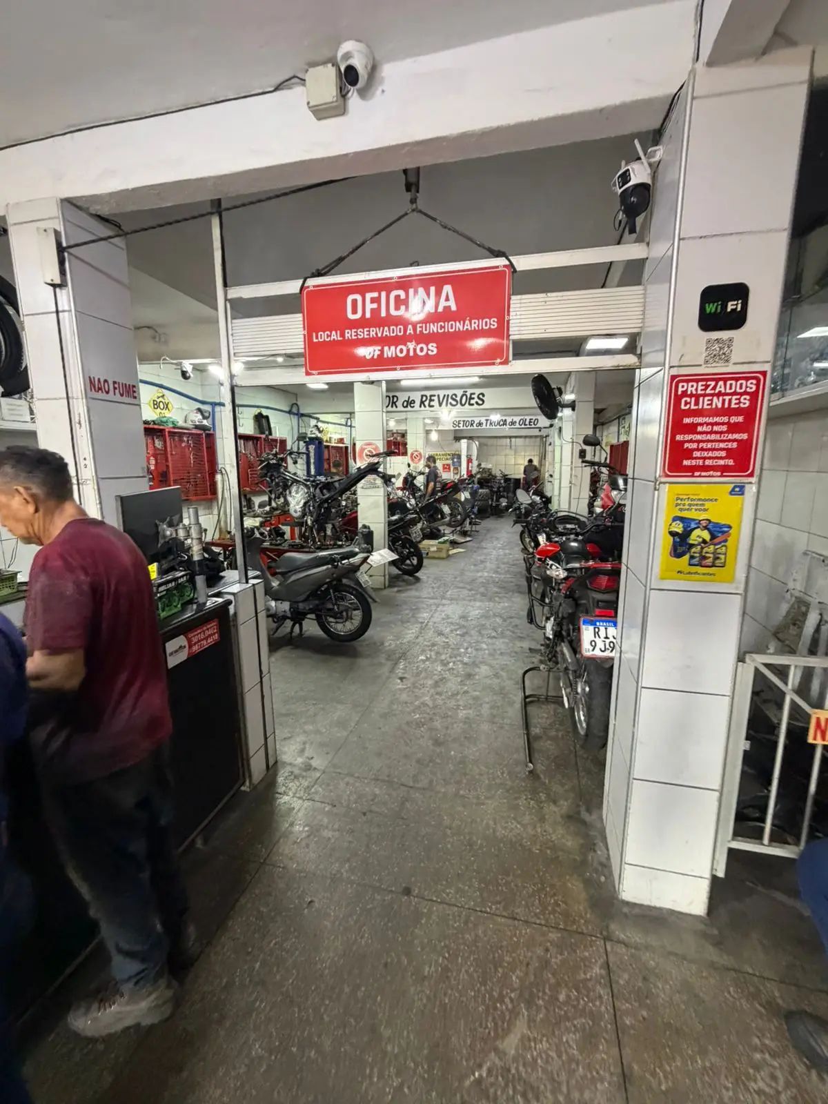 Entrada da oficina DF Motos no Quintino Cunha, com balcão de atendimento e placa Oficina