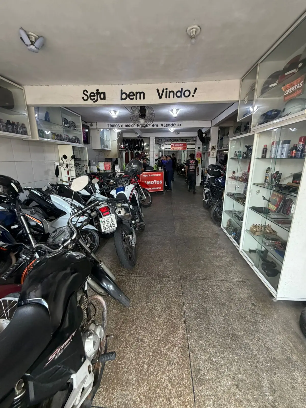 Loja da DF Motos com vitrines de peças, óleo, capacetes e acessórios para moto
